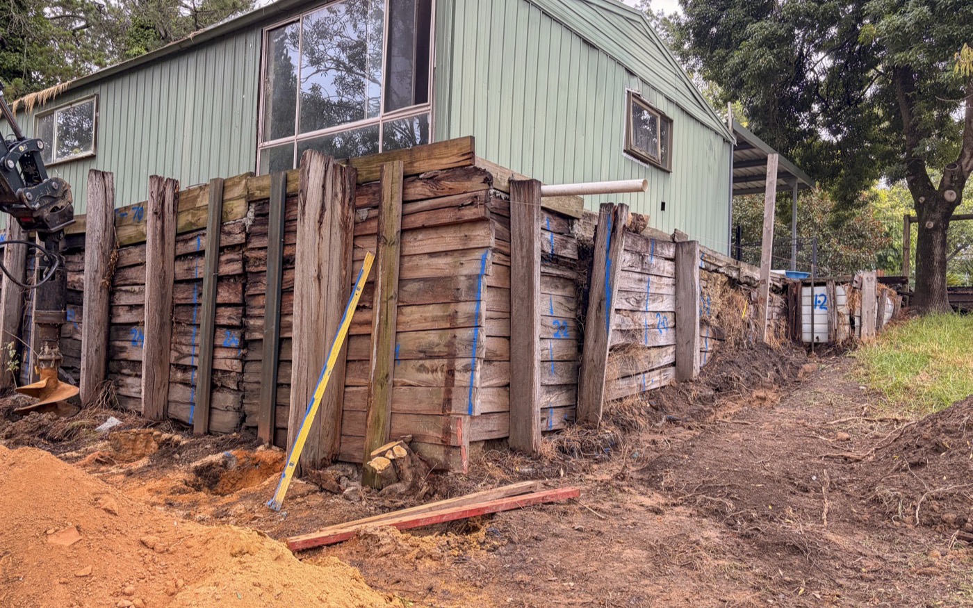Failed timber retaining wall leaning away from the bank it was holding