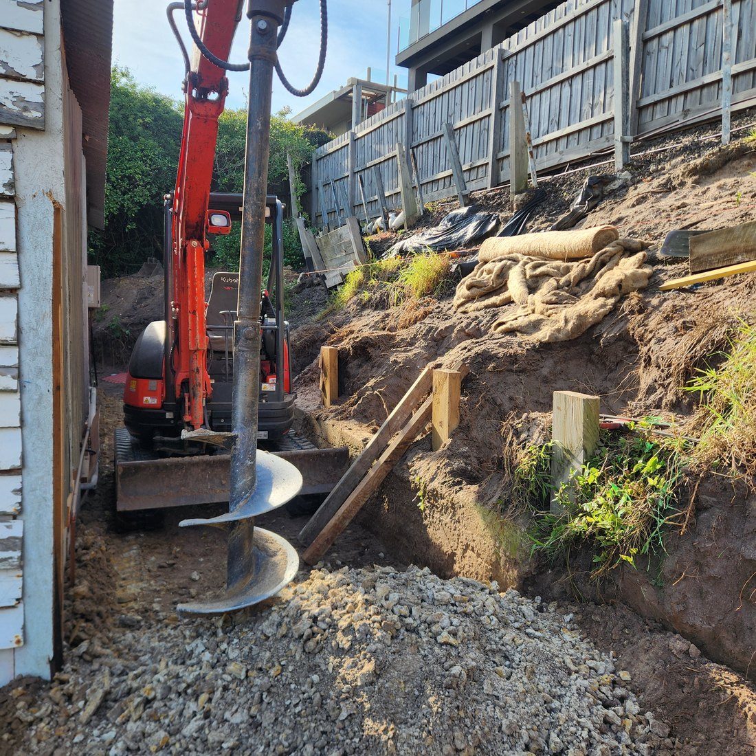 Auger drilling a footing in the corridor beside the house