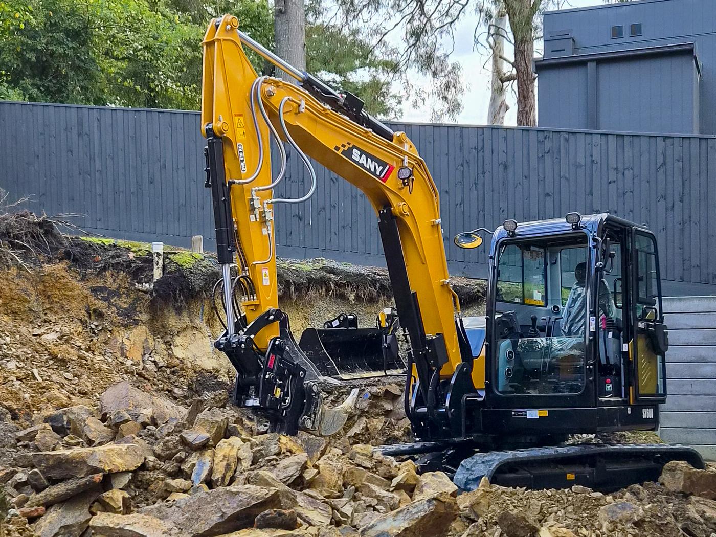 Excavator cutting a bench into a steep rock face