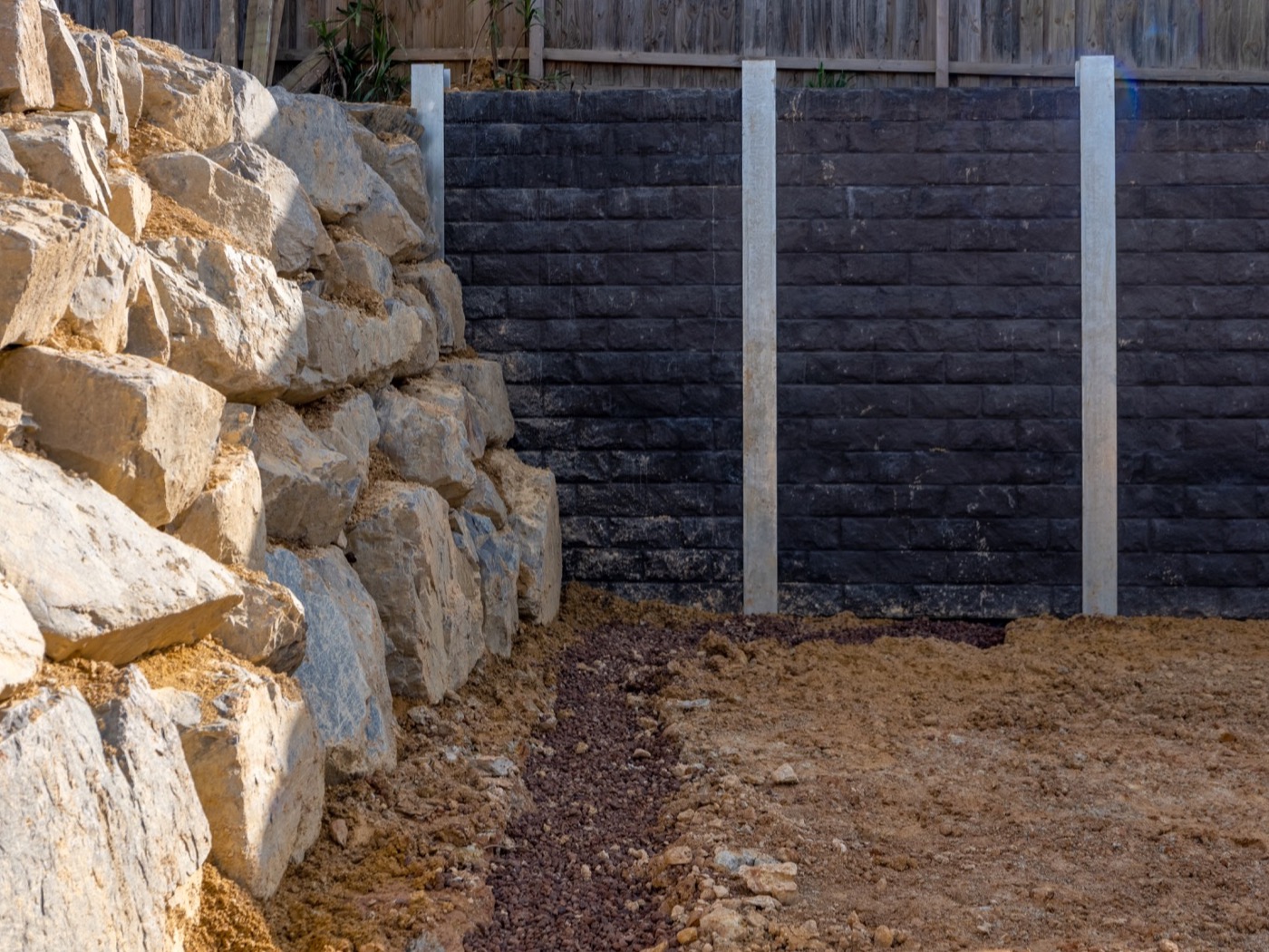 Large quarry boulders placed by machine against an engineered wall