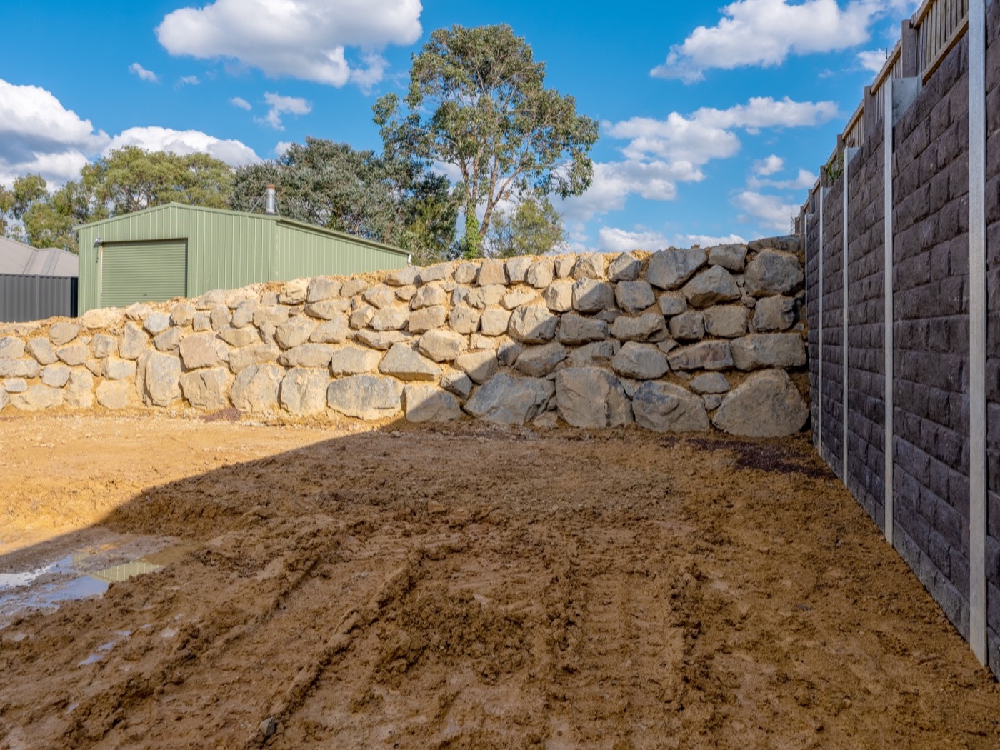 Transition between a quarry rock wall and a concrete sleeper retaining wall